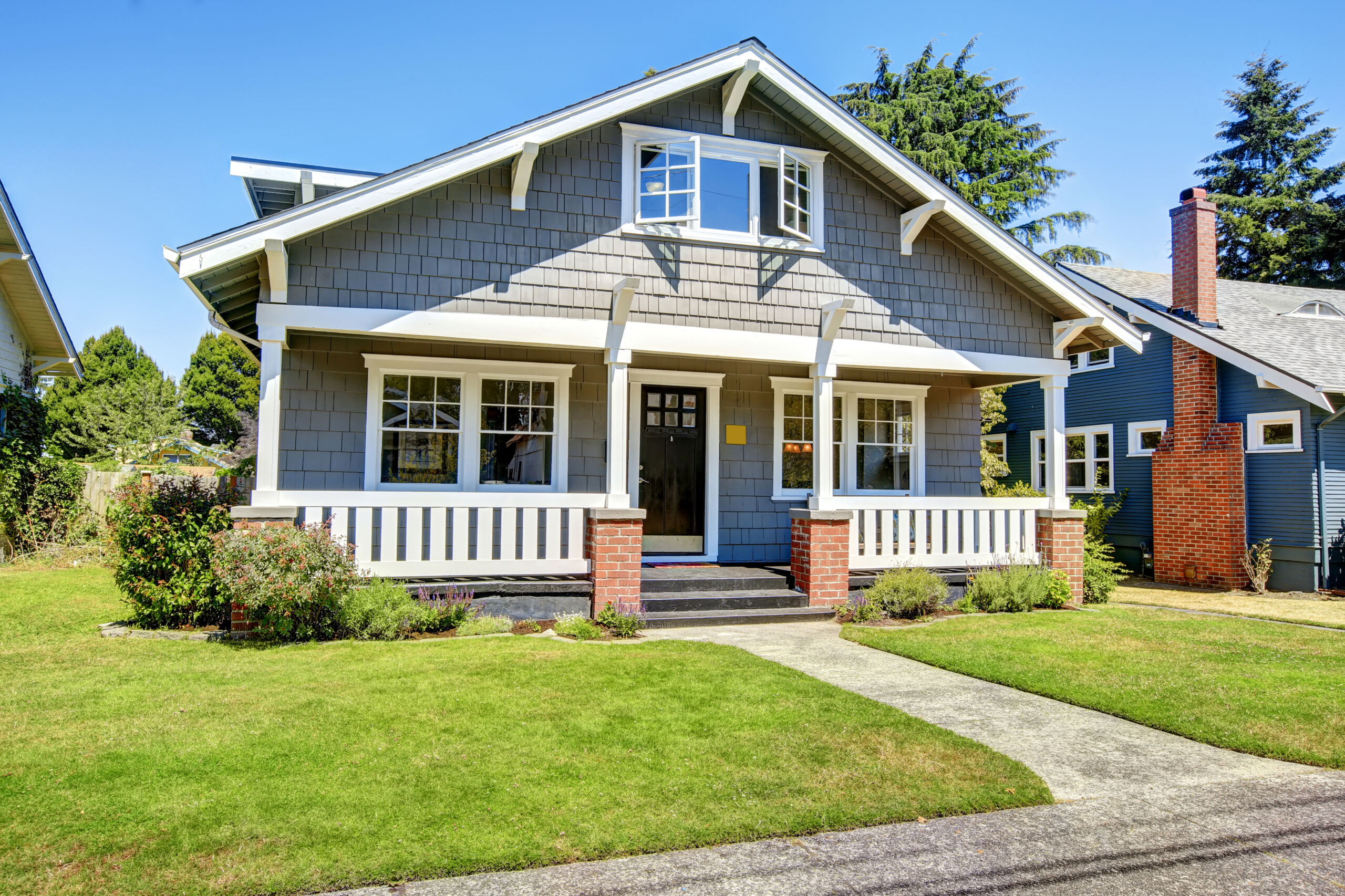 Clapboard siding house exterior. Large entance porch with brick